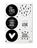 Twaalf ronde kerststickers van het merk Zoedt in zwart en wit op twee vellen papier.
