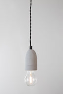 Zuiver hanglamp van grijs beton met zwart detail en zwart snoer