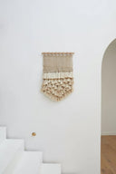 Handgemaakt jute wandkleed met kwastjes in een naturel kleur.