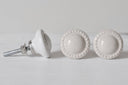 Kleine, gebolde meubelknop in creme kleur met decoratieve rand